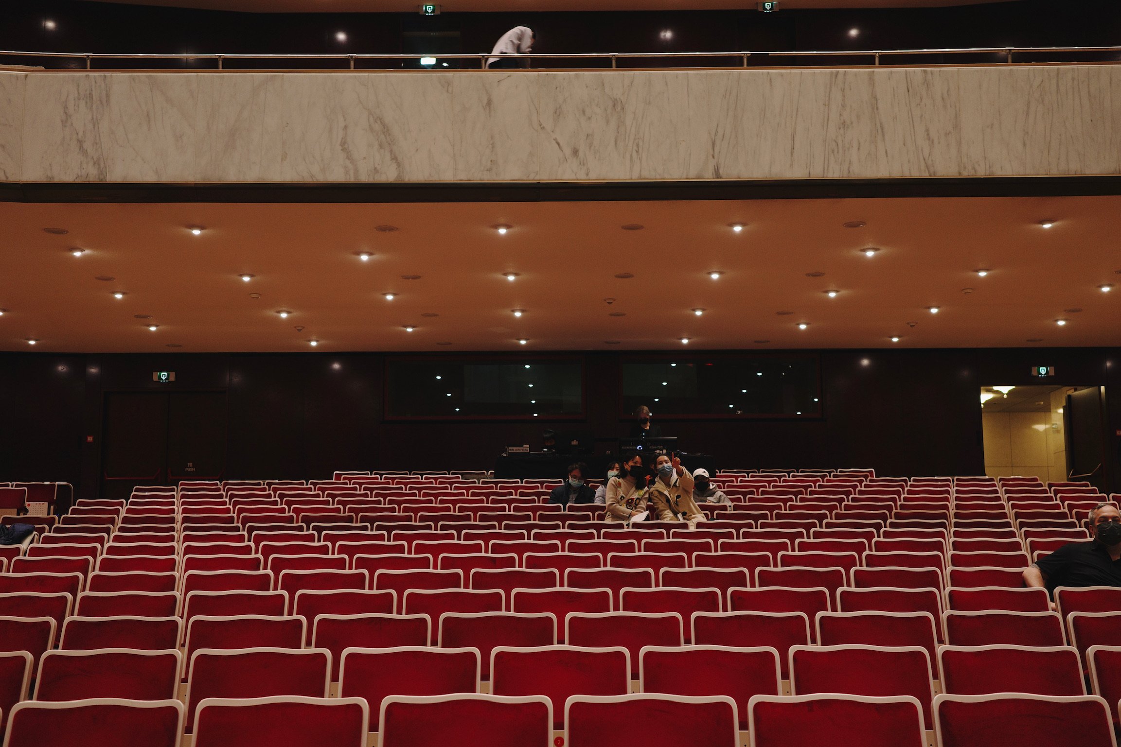 Red velvet seats and balconies in a concert hall. At the back, the PA station can be seen.