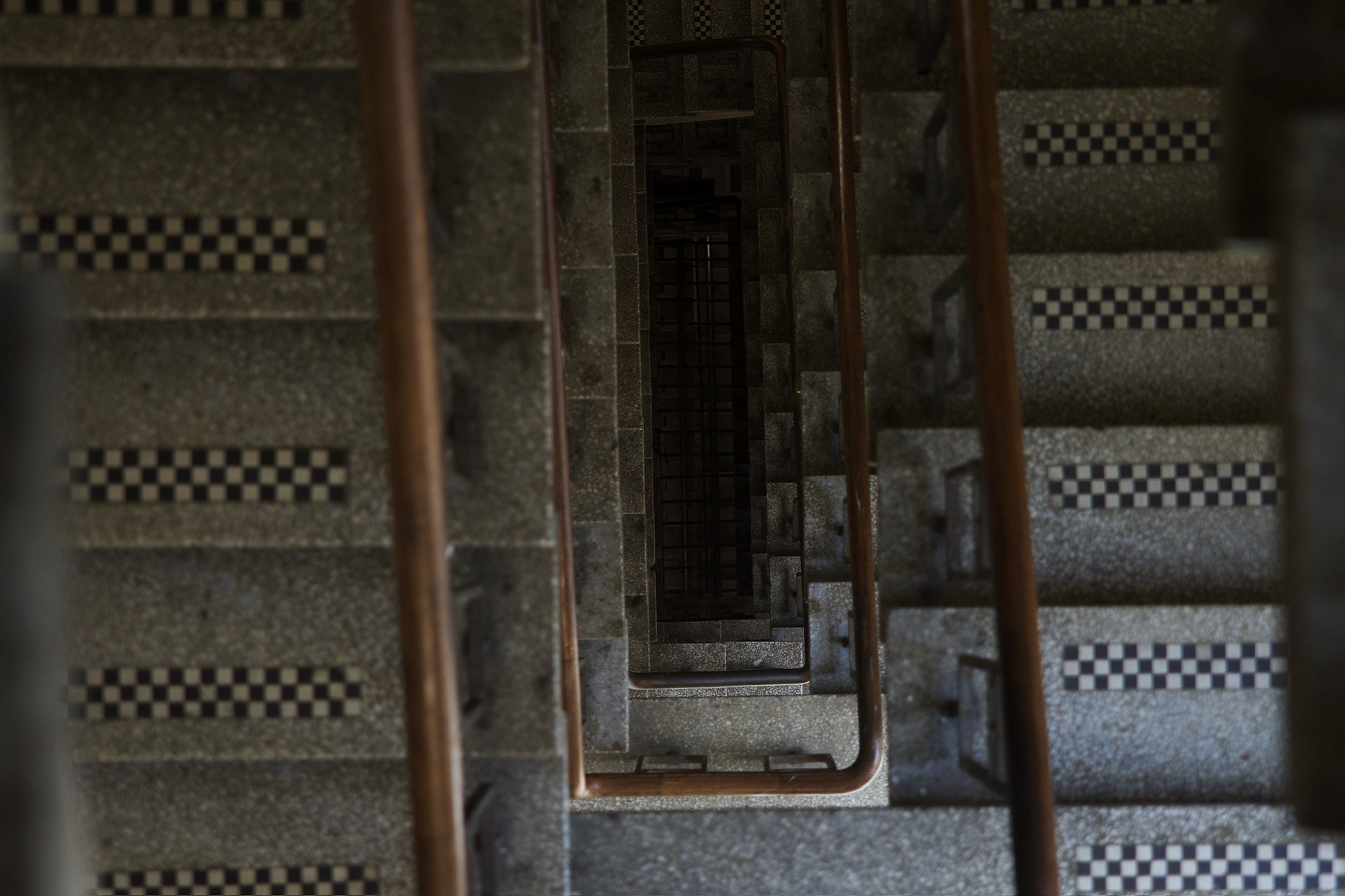a top down shot of a staircase with metal railings and checker patterns on the steps