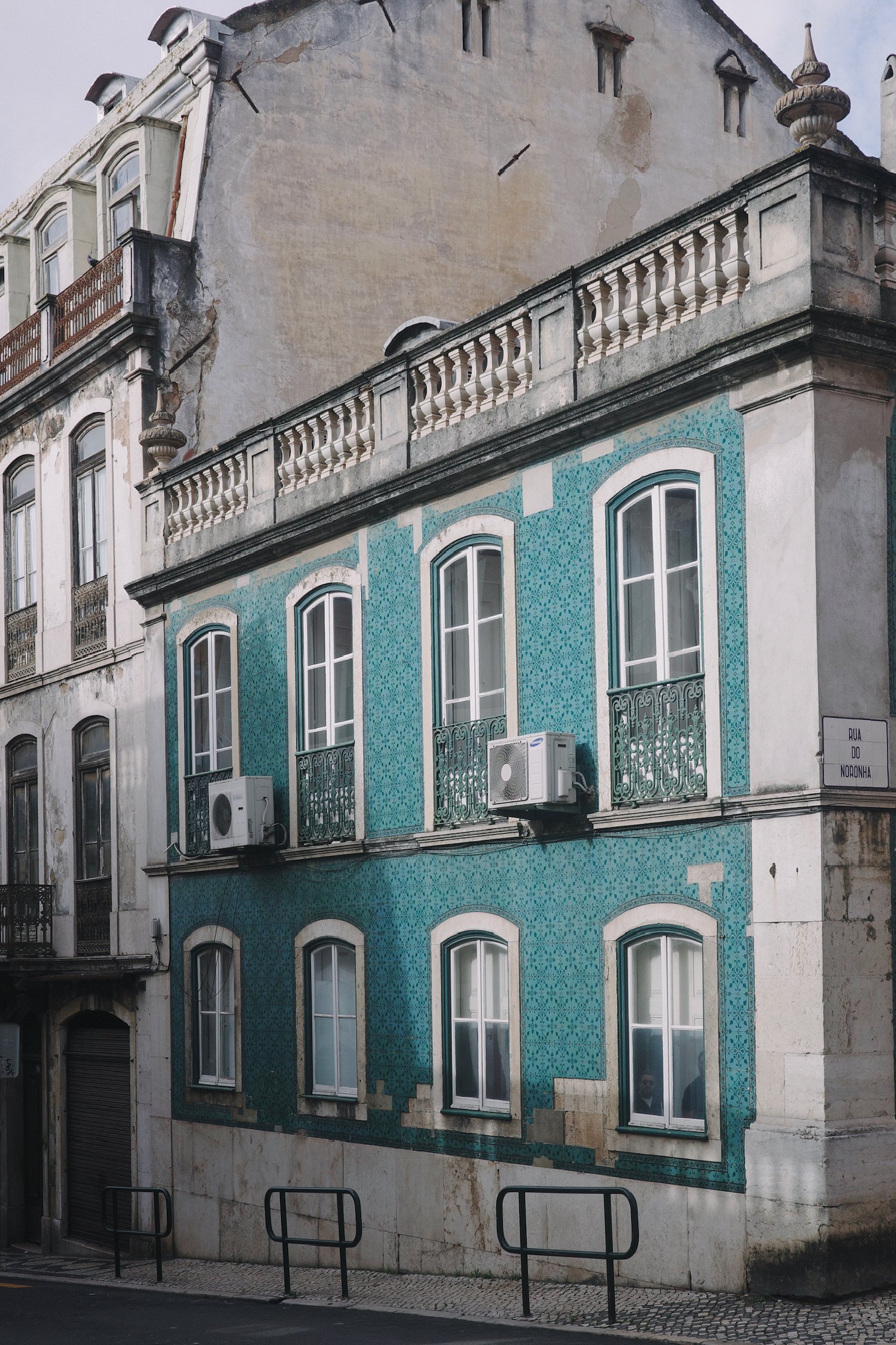 Teal tiled 2-story building with tall windows and outside AC units.