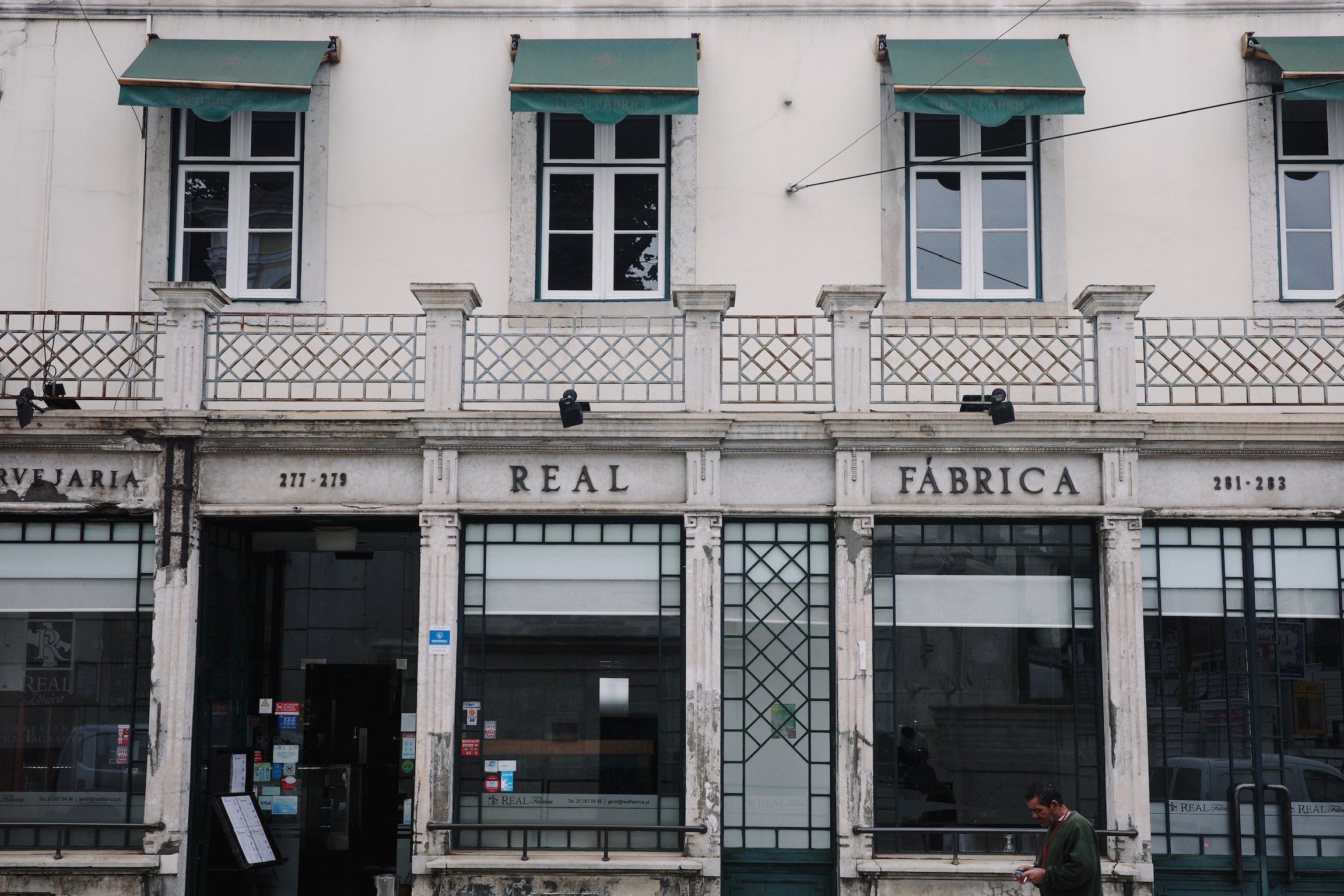 Exterior of Real Fabrica, a roaster, with dark green window/door frames and white walls.
