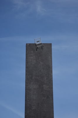 a shopping cart on top of a tall concrete tower.