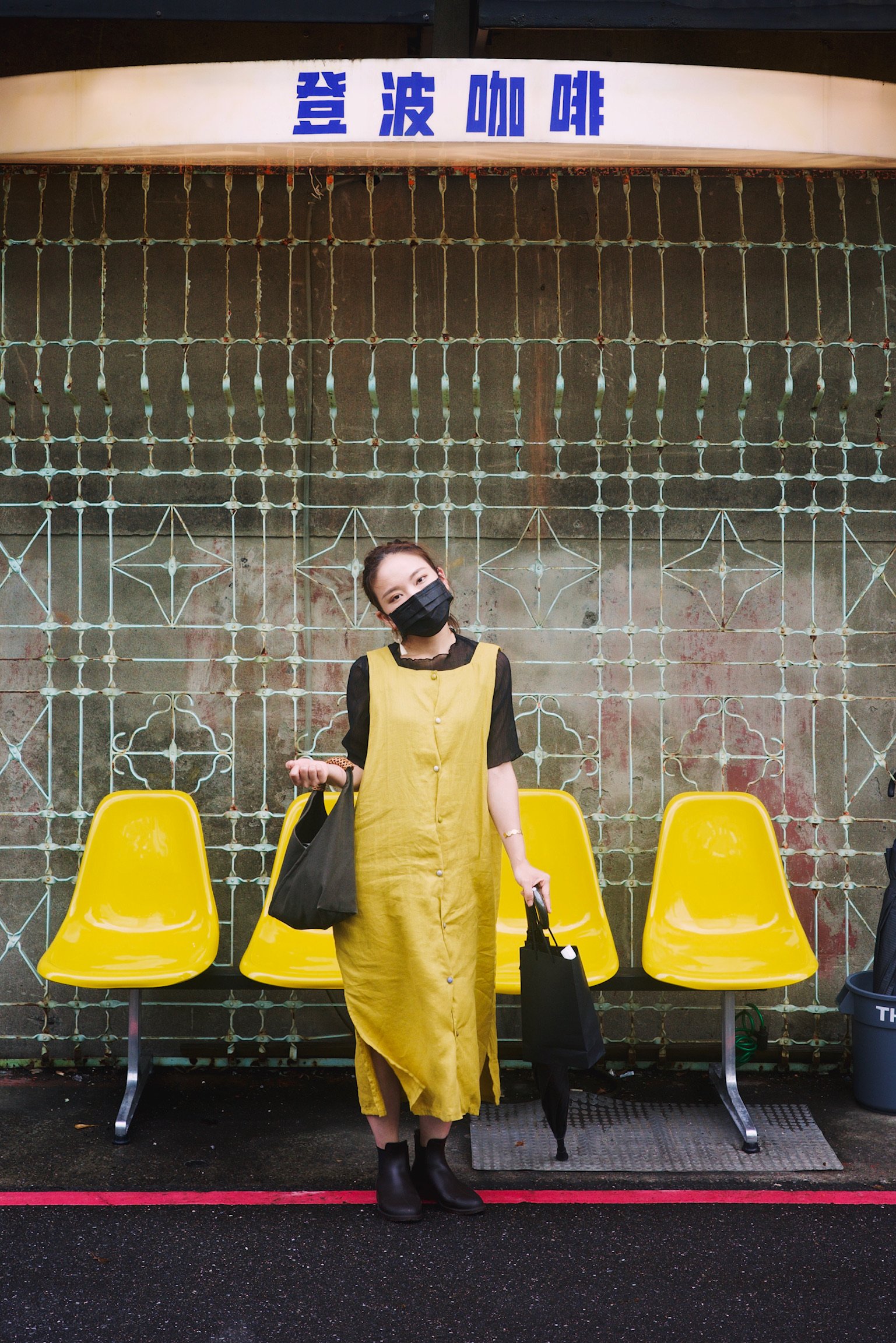 Woman wearing a yellow dress standing in front of a row of bright yellow chairs.