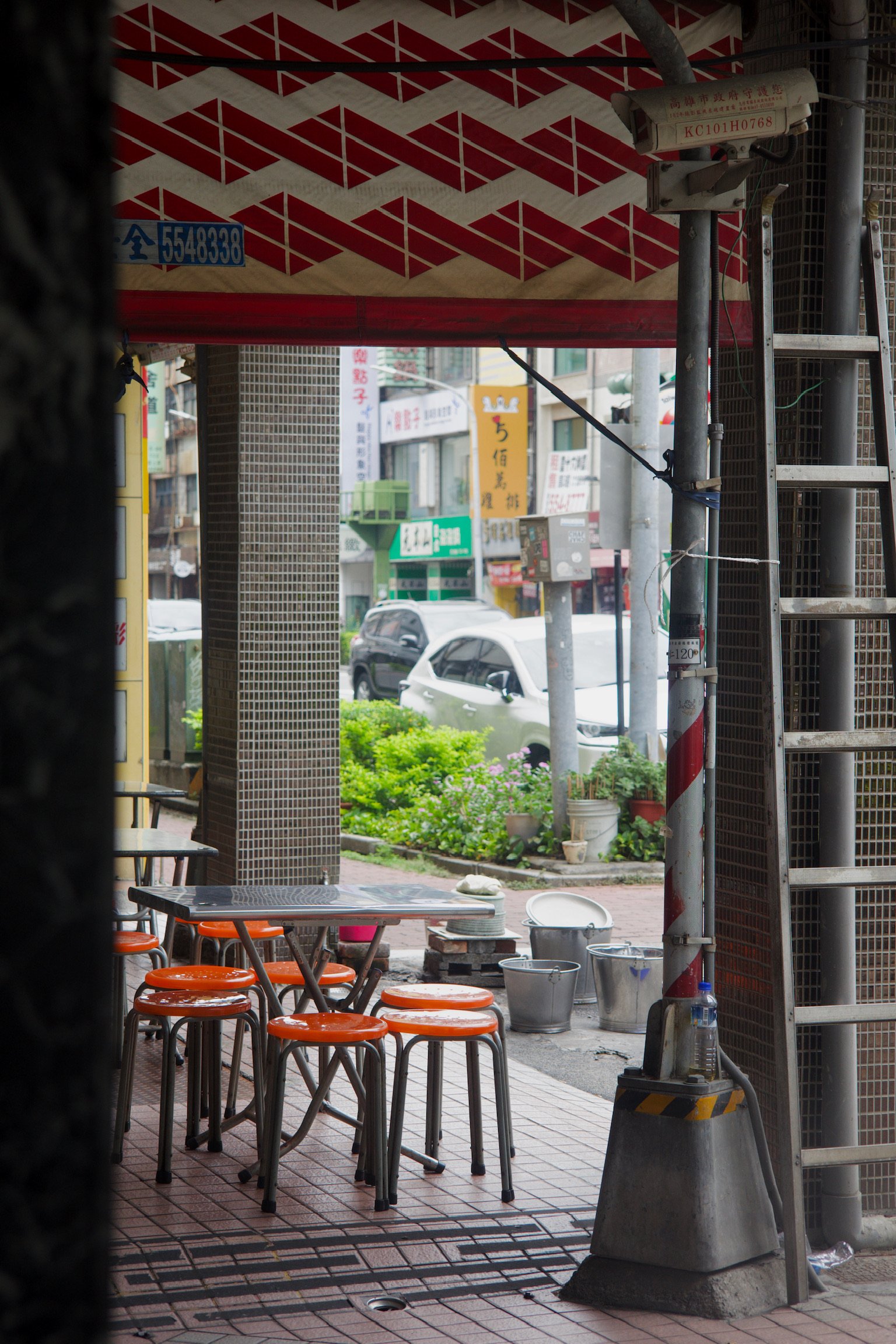 tables and chairs in bright orange under street overhang and a zigzag red and white pattern banner