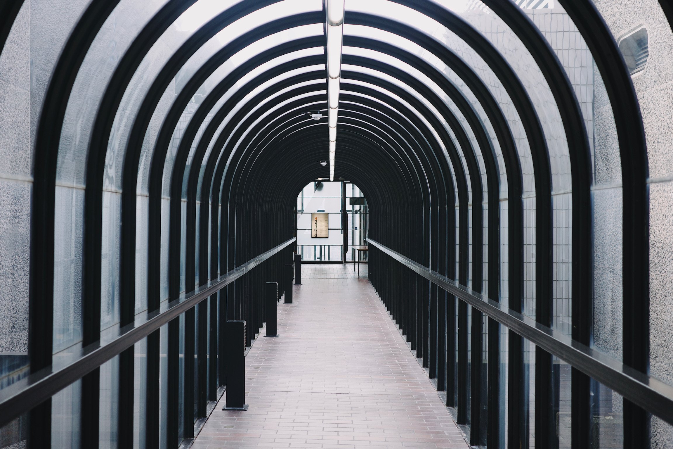 An archway connecting buildings with glass panels and black metal structure.