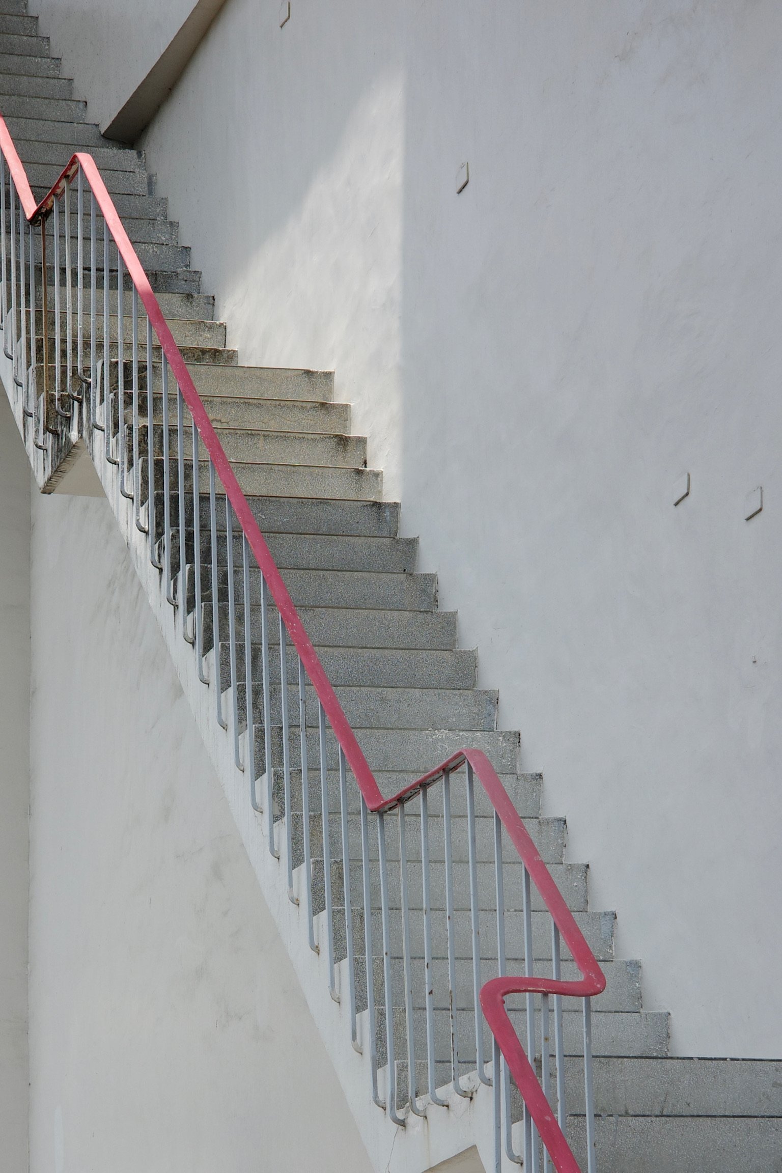a staircase with red railing with platforms in between.