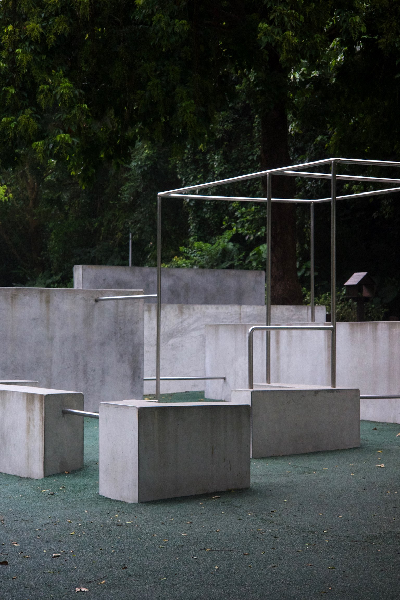 Concrete blocks of varying sizes and monkey bars in a park with lots of trees.